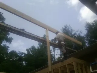Carpenter setting a ridge beam over a new addition frame — Ice Dam Removal by Roofing Brothers in Dauphin Island