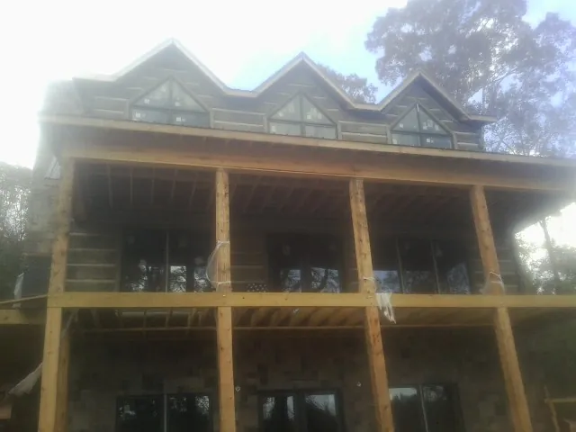 Dormers and porch framing on a large log home under construction — Roof Coating work by our crew in Dauphin Island