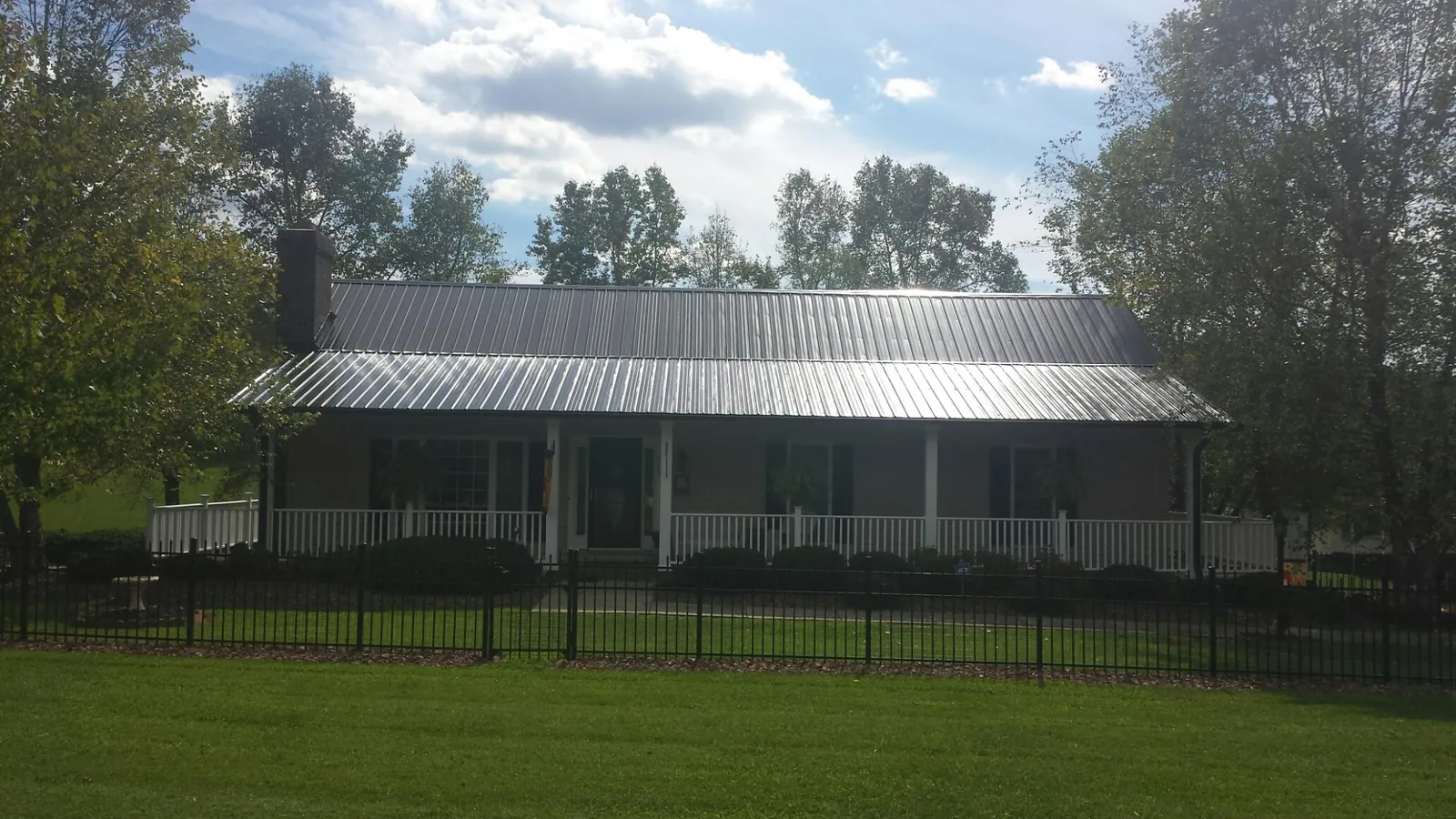 Gray metal roof on a brick ranch with a full width front porch — Gutter Guard Installation work by our crew in Dauphin Island
