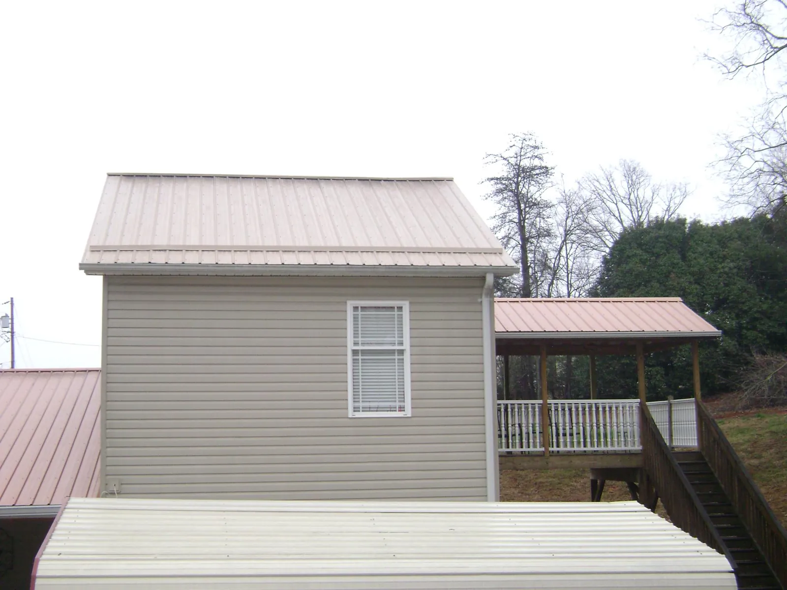 Tan metal roofs on a two story addition and attached porch, from a Roof Replacement job in Dauphin Island