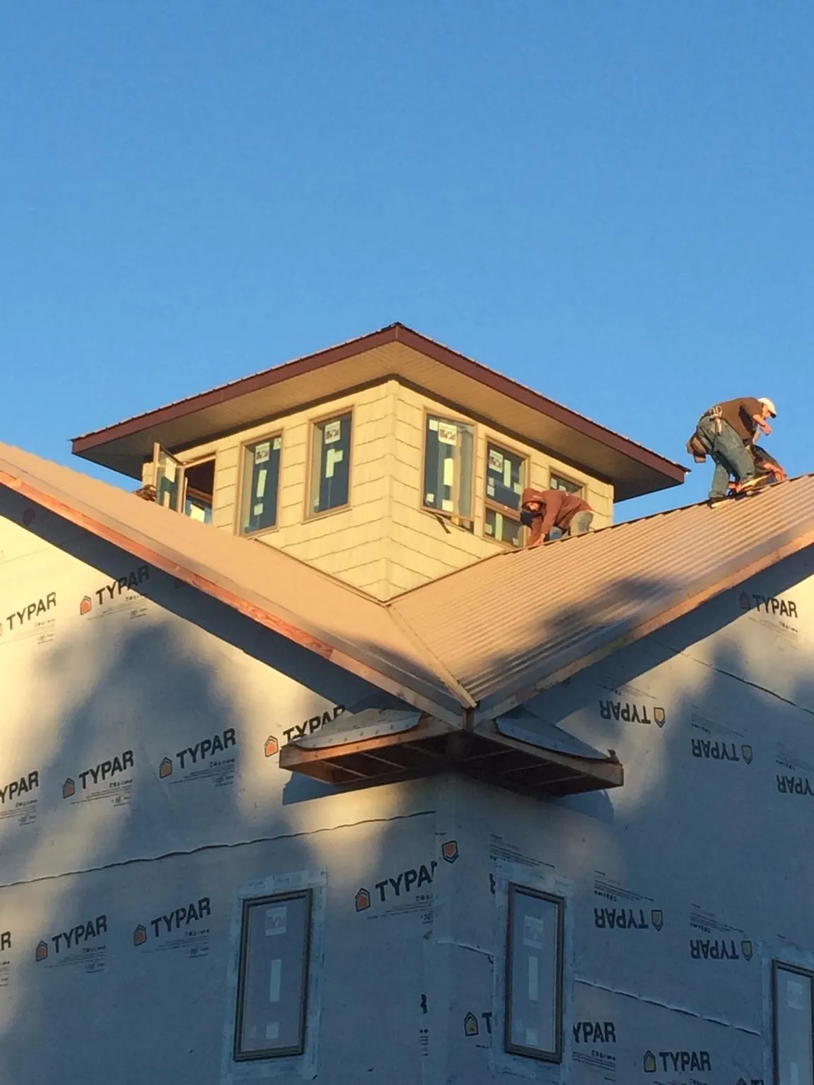 Roofers working around a rooftop cupola on a new metal roof at sunset — Roof Waterproofing in Dauphin Island by Roofing Brothers